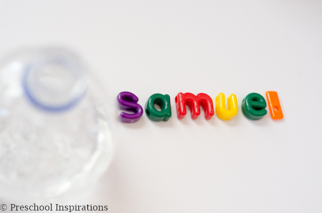 colorful alphabet beads spelling the name 'samuel' next to a plastic water bottle with hair gel