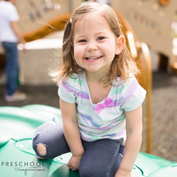 a grinning toddler plays on the playground